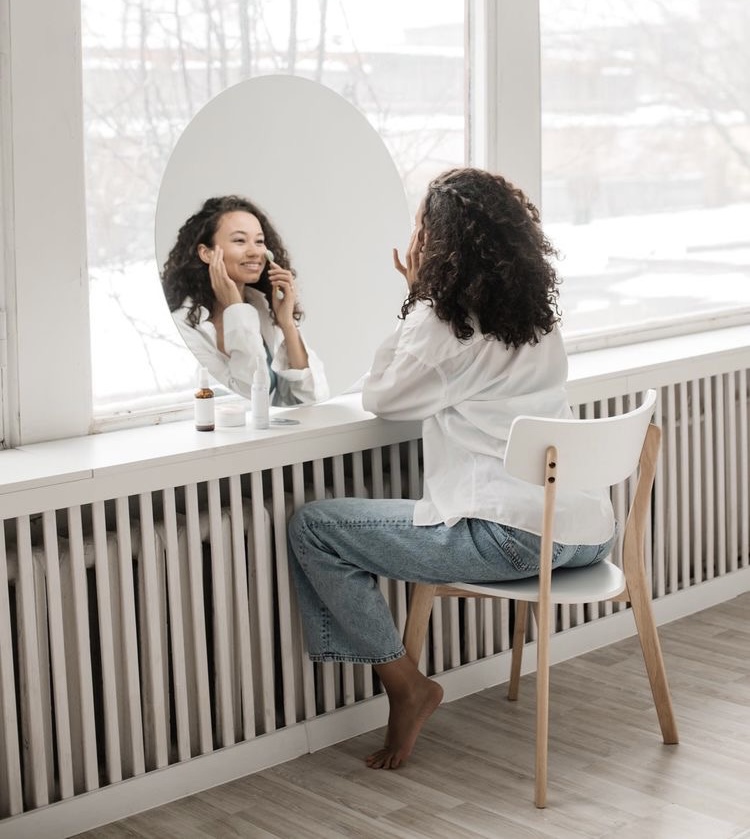 healthy living tips. Tips for healthy lifestyle . create and commit to a skincare routine. curly haired black woman sitting doing her skincare