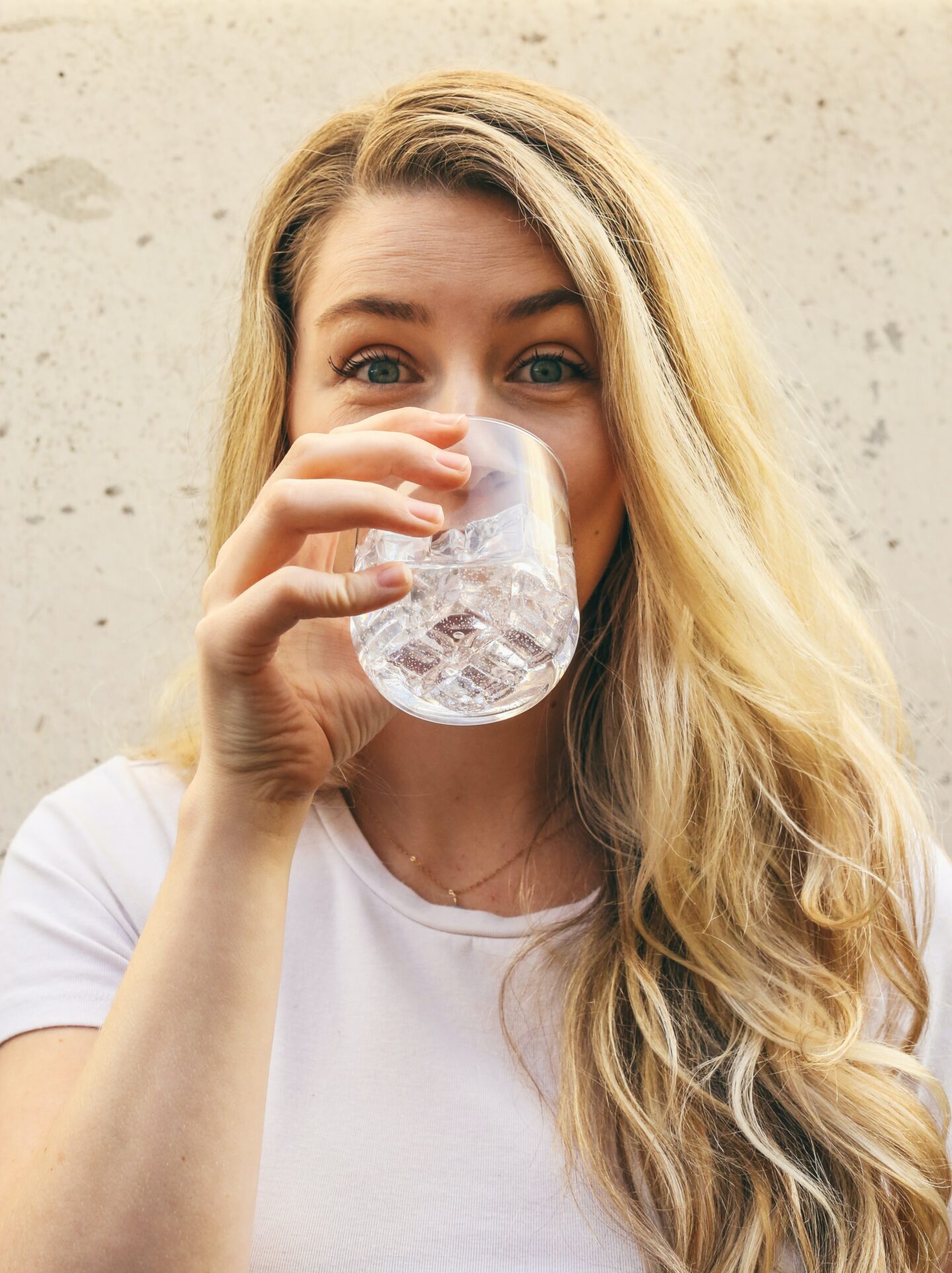 12 simple ways to drink more water every day. Happy woman drinking a glass of water