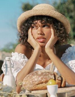 beautiful black woman with curly hair and summer hat having a picnic. beautiful woman in the summer. Summer self-care ideas