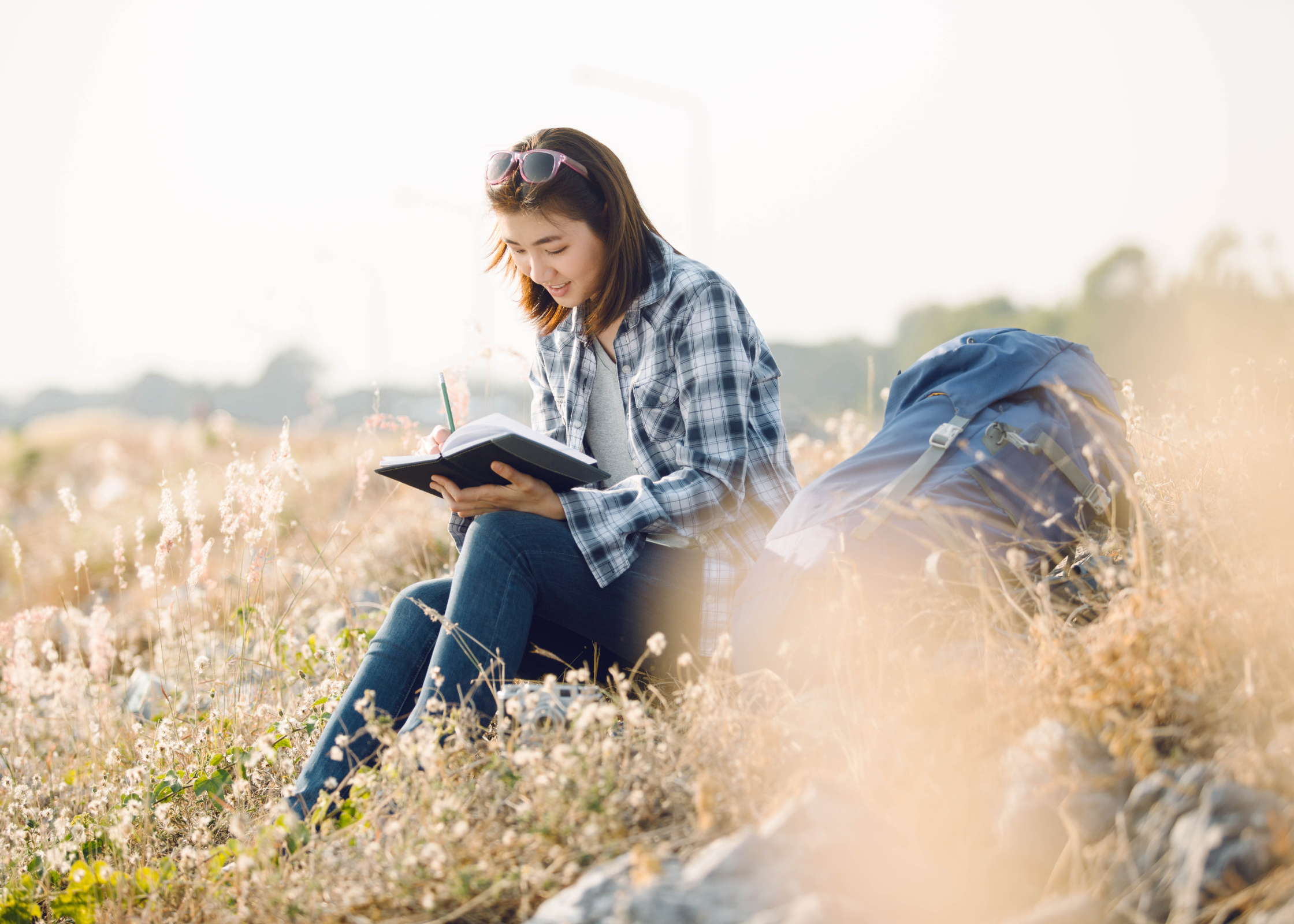 woman journaling and writing whilst sitting in a field. how to glow up. glow up tips. how to glow up in a week. How to glow up overnight. how to get a glow up. how to have a glow up. glow ups. how to be beautiful. fast and instant glowing up tips
