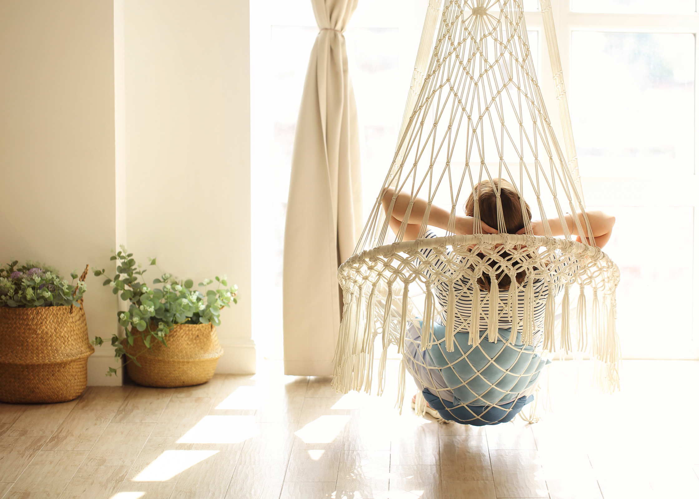 woman sitting on a hammock relaxing looking out of the window with sunlight coming through, how to take time for yourself. self care ideas for mind body and soul. self-care ideas for mental health. me time ideas