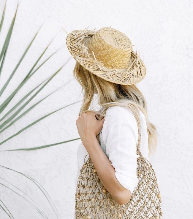 woman in straw summer hat with a woven beach bag. modest summer beach look outfit style