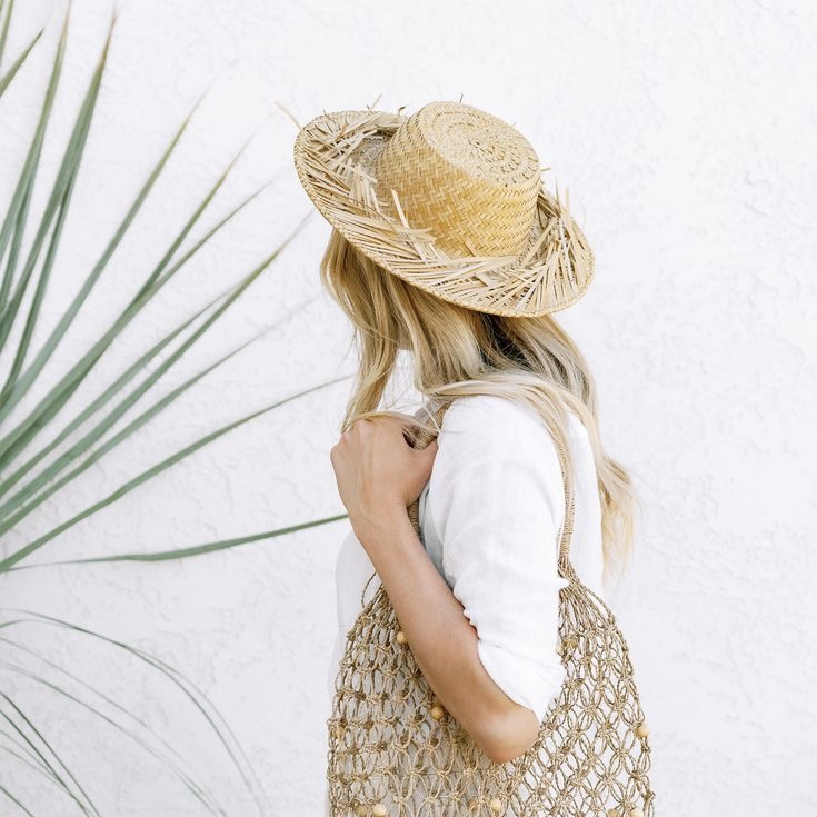 woman in straw summer hat with a woven beach bag. modest summer beach look outfit style