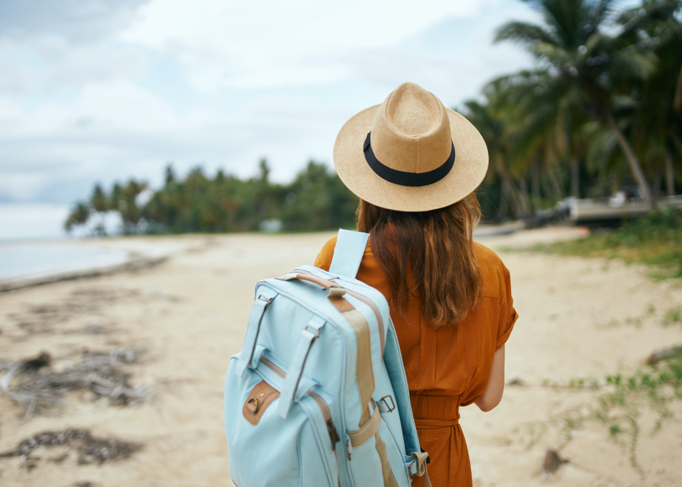 healthy eating on holiday. stay healthy on holiday. healthy holiday tips. staying healthy on vacation. mindful eating on holiday. healthy travel tips. woman holding a backpack on the beach